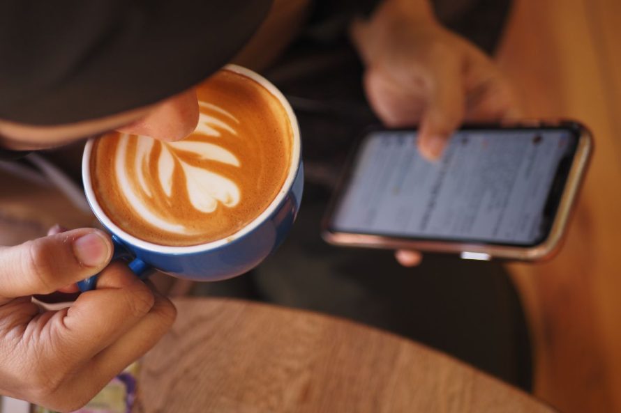 3 person checking phone cafe